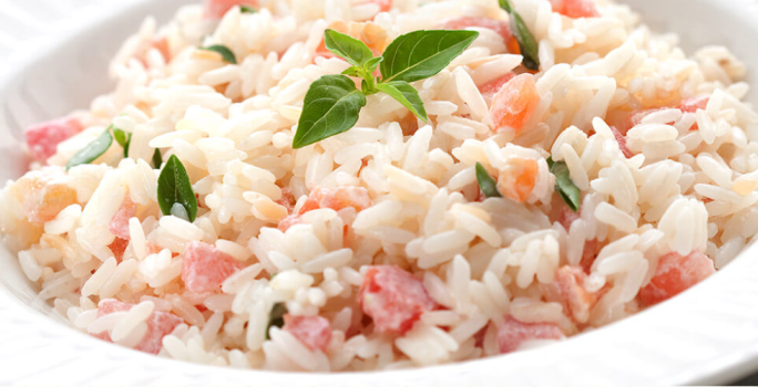 foto em tons de branco e vermelho tirada de um prato redondo branco com arroz e tomate