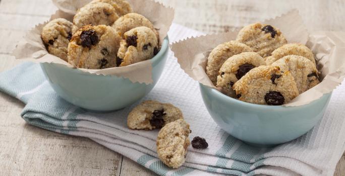 Fotografia em tons de branco e azul de uma bancada branca com um paninho azul e branco, sobre ele dois recipiente redondos azuis com biscoitinhos.