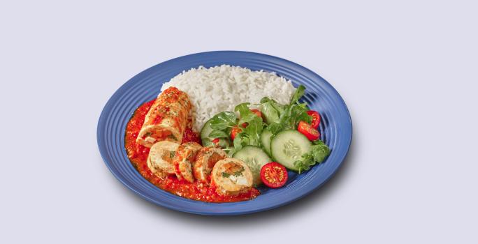 Fotografia em tons de azul em um fundo branco, ao centro um prato azul com arroz, salada verde e o filé de frango à rolê.
