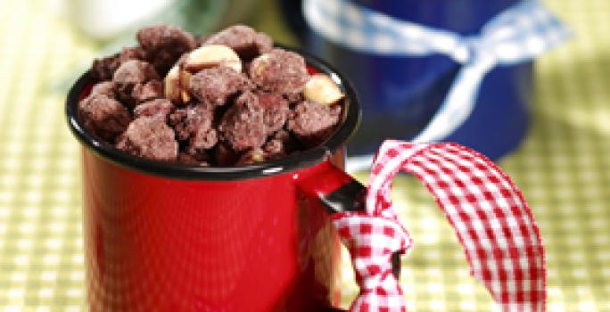 Fotografia em tons de verde, branco e vermelho de uma toalha xadrez verde e branco, sobre ela xícaras com amendoim praline.