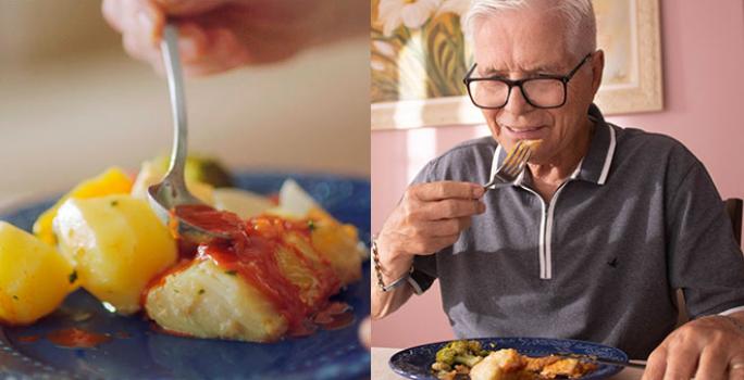 foto dividida ao meio: do lado esquerdo uma cena bem aproximada de uma garfada na receita de Bacalhau à Portuguesa servida em um prato azul; do lado direito, um senhor mais velho de óculos experimentando um pedaço da mesma receita
