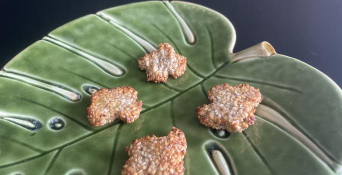 Imagem da receita de Biscoito de Banana e Gergelim em um recipiente de vidro em formato de folha verde