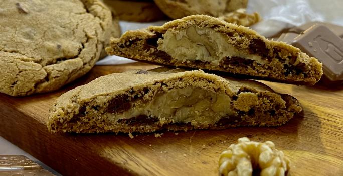 Foto da receita de Cookies recheados de nozes. Na foto observa-se cookies dispostos sobre uma tábua de madeira.
