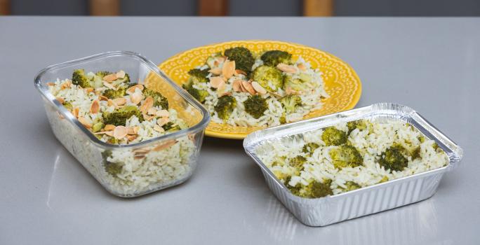 Foto da receita de Arroz com Brócolis em uma vasilha de vidro, uma forma de alumínio e sobre um prato amarelo, em cima de uma bancada