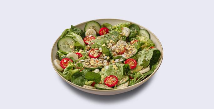 Fotografia em tons de verde em um fundo branco com um prato fundo redondo com a salada verde.