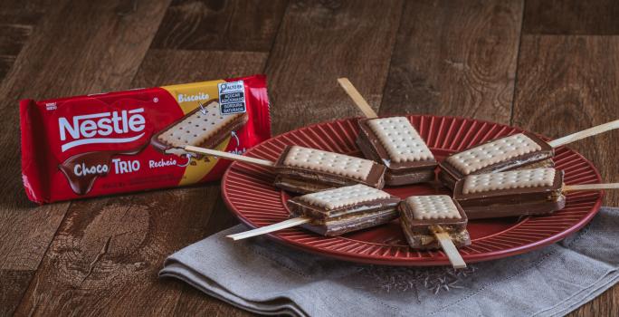 Foto da receita de    Receita de Pirulito de Paçoca com Choco Trio Amendoim. Observa-se 6 pirulitos dispostos em um prato vermelho redondo sobre um pano cinza.