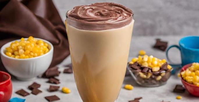 Fotografia de um copo alto com um creme amarelo, com uma cobertura de chocolate.