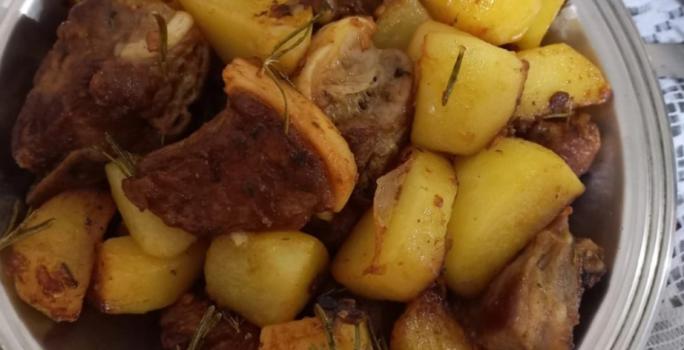 Foto da Receita de Costelinha de Porco com Batatas Salteadas no Alecrim. Observa-se um prato grande de servir de alumínio com as costelinhas e as batatas dispostas.