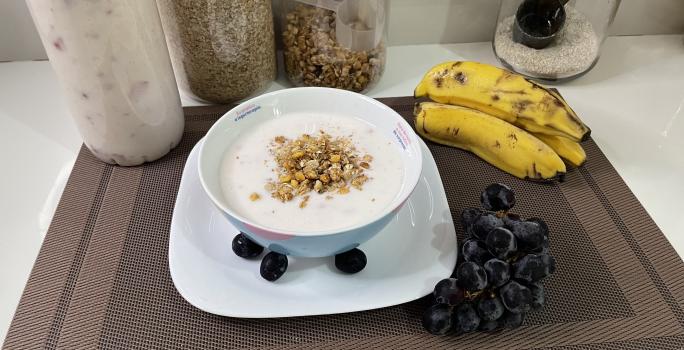 Imagem da receita de Iogurte Caseiro de Morango em um bowl, sobre uma mesa com bananas e uvas ao lado