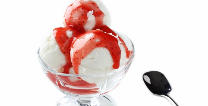 fotografia em tons de branco e vermelho tirada de uma taça de sorvete com calda de frutas vermelhas