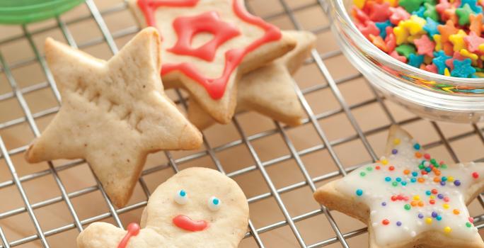 Fotografia de biscoitos decorados de natal em formato de boneco, estrela e presentes, nas cores vermelho, verde e branco, decorados com confeitos das mesmas cores.