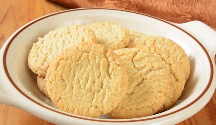 Em cima de uma mesa, prato redondo com biscoitos redondos crocantes e dourados.