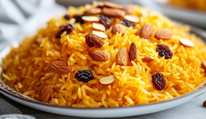 Prato redondo com porção de arroz soltinho com amêndoas e uvas-passas pretas.