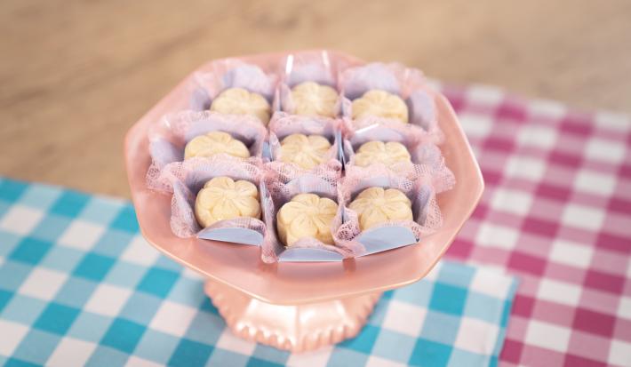 Fotografia de brigadeiros de leite ninho em formato de pétalas sobre forminhas azuis e rosa