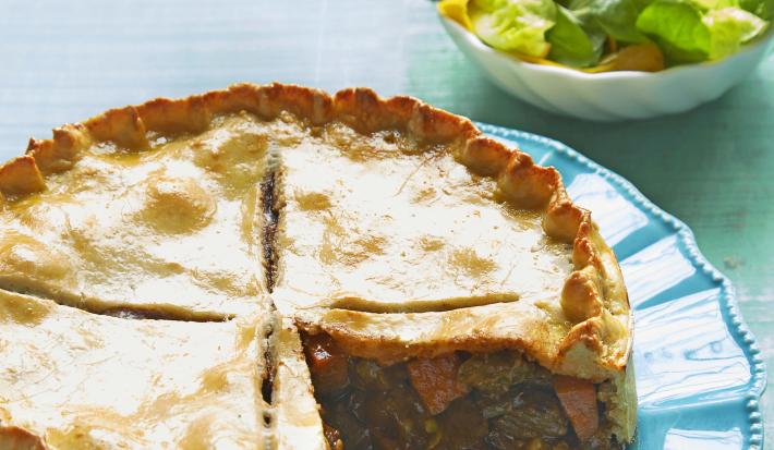 em um prato redondo e azul contém uma torta com uma fatia retirada e ao lado um pote branco e redondo com folhas.