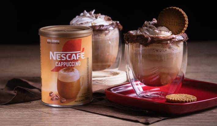 Foto da receita de cappuccino avelã servida em dois copos de vidro sobre um pano marrom