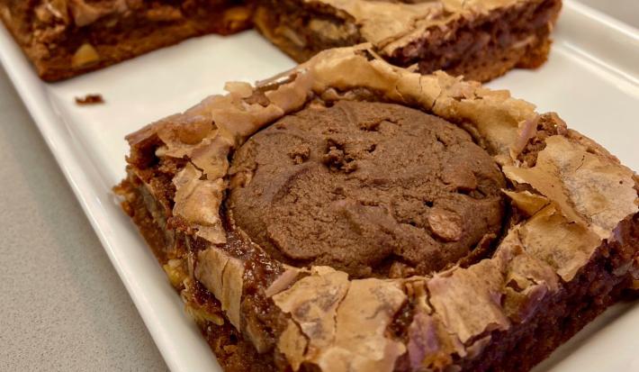 Fotografia mostra um brownie de chocolate com um cookie de chocolate em cima.