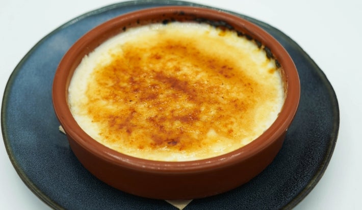 Em uma refratário redondo marrom, porção de queijo gratinado marrom.