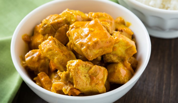 Fotografia de um frango em cubos temperado com molho de curry