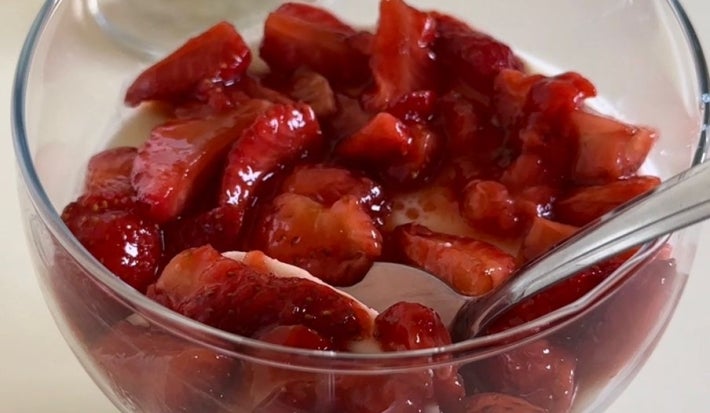 Fotografia de dois recipientes pequenos de vidro fundos sobre uma mesa branca. Dentro dos recipientes têm uma a receita de Panna Cotta com Morango e Vinagre Balsâmico.