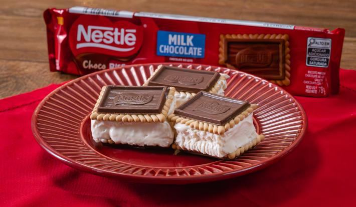 Fotografia em tons de vermelho com um prato vermelho ao centro. Em cima do prato existe 3 biscoitos Choco Biscuit recheados com sorvete de creme.