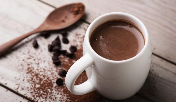 Foto da receita de Chocolate Quente. Observa-se uma xícara branca com a bebida cremosa dentro.