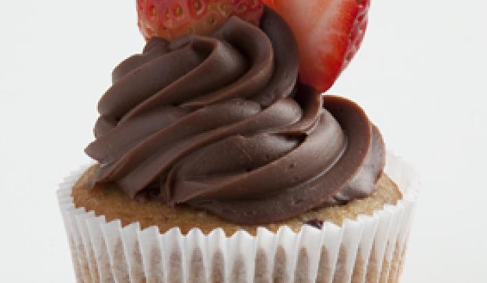 um bolinho com cobertura de chocolate por cima e frutas vermelhas para decorar