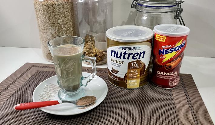 Imagem da receita de Cappuccino Proteico, sobre uma mesa, ao lado uma lata de Nutren Protein e Nescau Canela