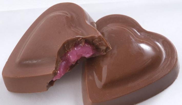 fotografia em tons de marrom e branco tirada de dois bombons em formatos de coração, e um deles esta sem um pedaço mostrando o recheio