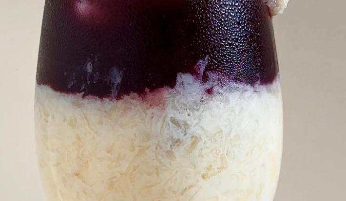 Fotografia em tons claros de uma taça de vidro com uma espanhola de abacaxi sem álcool.