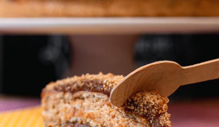 Foto da receita de Pavê Delícia. Observa-se uma fatia do pavê sendo cortado por uma colher de madeira.