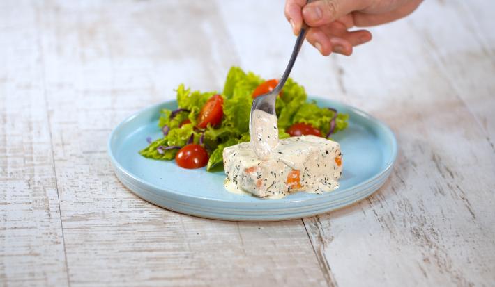 Fotografia em tons de branco e azul de uma bancada branca, sobre ela um prato redondo azul com salão e salada.