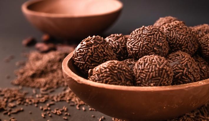 Imagem de um bowl marrom com brigadeiros feito com whey com chocolate granulado.