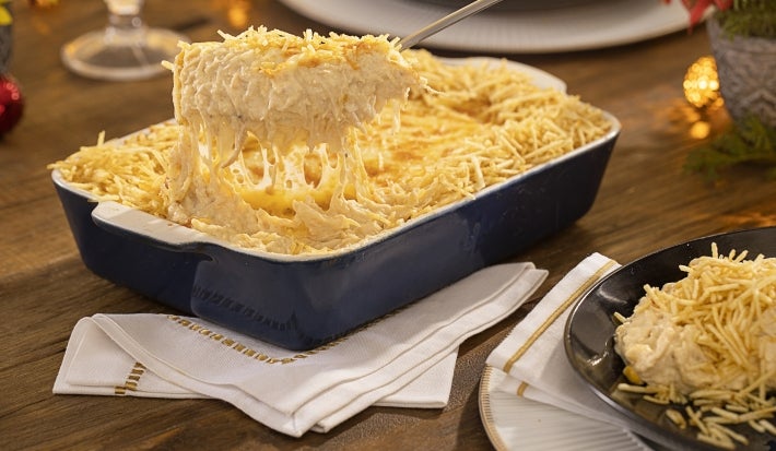 Travessa azul com fricassê de frango com milho e batata palha com uma colher tirando um pedaço. Travessa azul com fricassê de frango com milho e batata palha com uma colher tirando um pedaço.