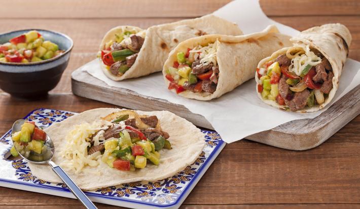 Em uma mesa de madeira contém duas tábuas, uma contem a fajita aberta e na outra de madeira contém três fechadas.