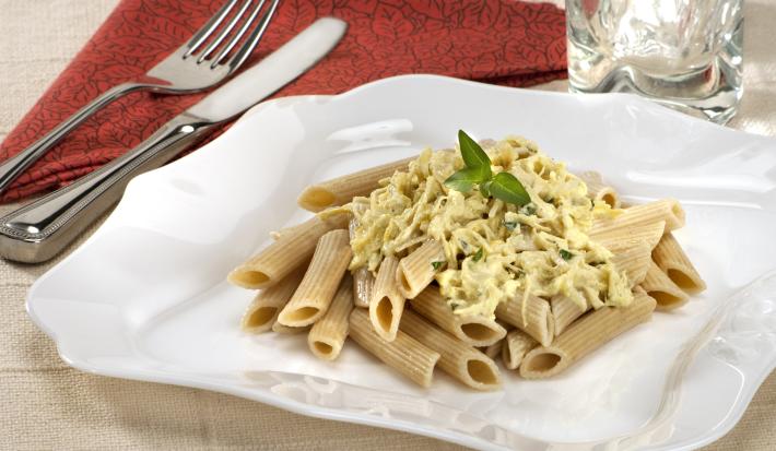 em um prato branco contém o macarrão. Ao lado, um pano na cor vermelha e por cima grafo e faca.