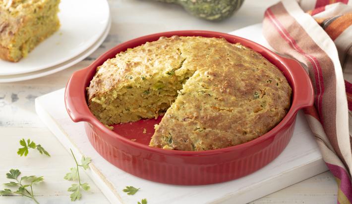 Foto da receita de Torta de Casca de Abóbora com Recheio de Talos. Observa-se a torta assada dentro de um recipiente refratário vermelho com um pedaço cortado