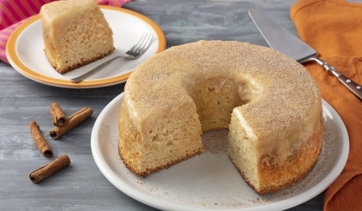 Prato branco com um bolo branco com cobertura de doce de leite sem lactose.