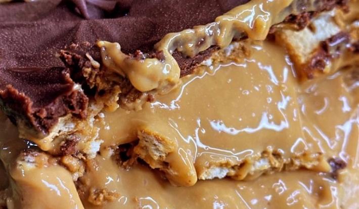 Foto da receita de Pavê de Doce de Leite com Café. Observa-se o pavê bem de perto com as chamadas, o topo de ganache e o doce de leite bem cremoso ao meio.