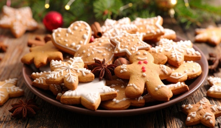 Em cima de uma mesa, prato redondo com biscoitos em formato de estrelas, decorados com açúcar de confeiteiro.