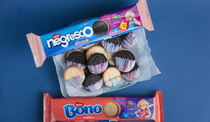 Biscoitos decorados com cobertura marmorizada azul, rosa e branca, com embalagens Negresco e Bono ao redor.