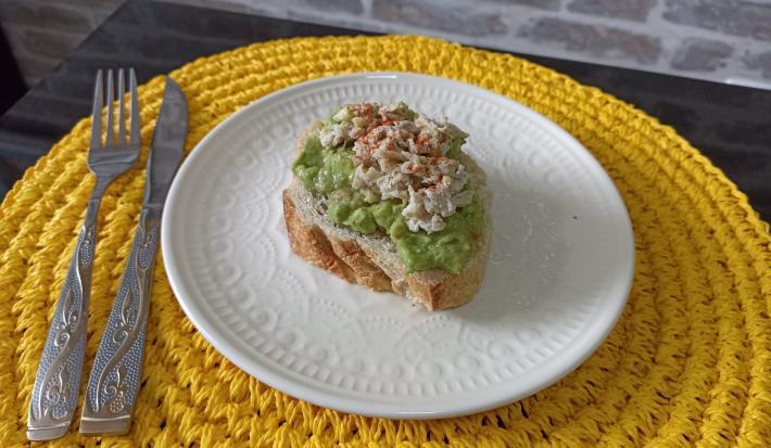 Imagem da receita de Avocado Toast, em um prato branco, sobre uma mesa e ao lado os talheres
