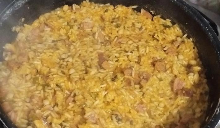 Fotografia de uma panela preta funda com uma receita de baião.