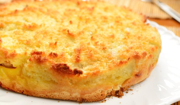imagem de uma torta dourada com a superfície crocante e levemente tostada, sobre um prato branco