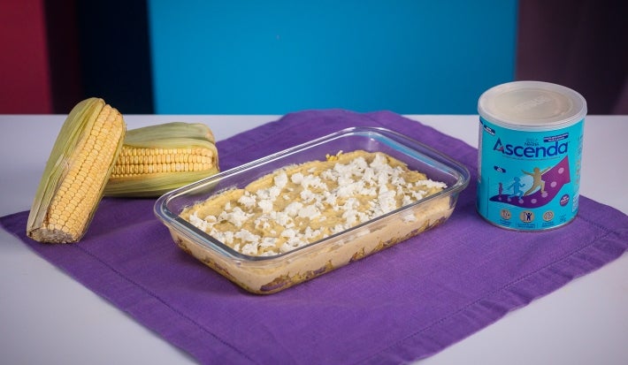 Fotografia em tons amarelo e roxo com uma travessa de vidro ao centro. Na travessa, existe uma receita de Fricassê de frango feita com Ascenda e finalizada com queijo branco.