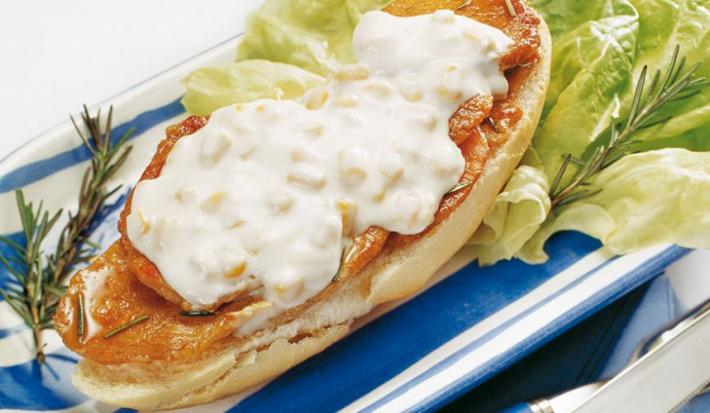 fotografia em tons de branco e azul tirada de uma bandeja azul com sanduiche com pedaços de lombo e creme branco por cima
