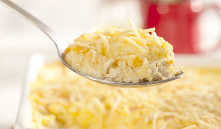 Travessa branca com fricassê de frango com milho e batata palha com uma colherada. Travessa branca com fricassê de frango com milho e batata palha com uma colherada.