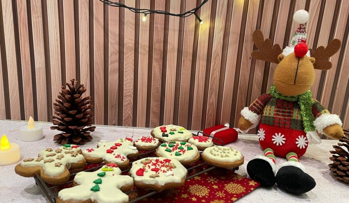 Fotografia em tons de vermelho com uma bandeja de biscoitos natalinos decorados ao centro.