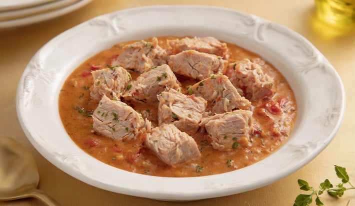 Goulash moderno de atum servido em prato fundo, com cubos de peixe em molho de tomate encorpado e ervas frescas.