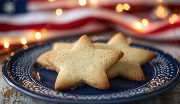 Em cima de uma mesa, prato azul redondo com biscoitos em formato de estrelas.